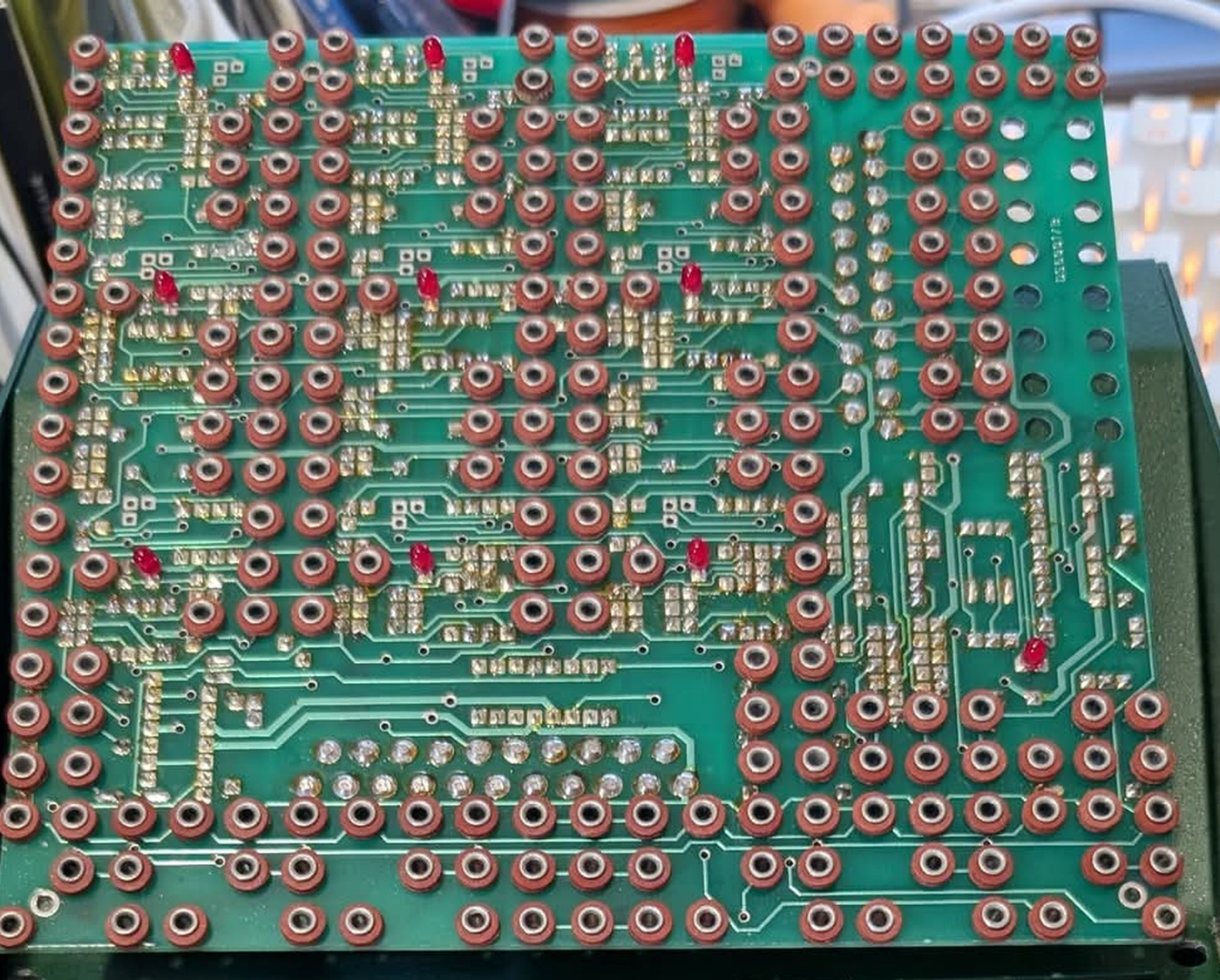 The underside of the lifted jack board, showing the grid of socket bodies, a few indicator LEDs protruding through, and the printed wiring that links them.